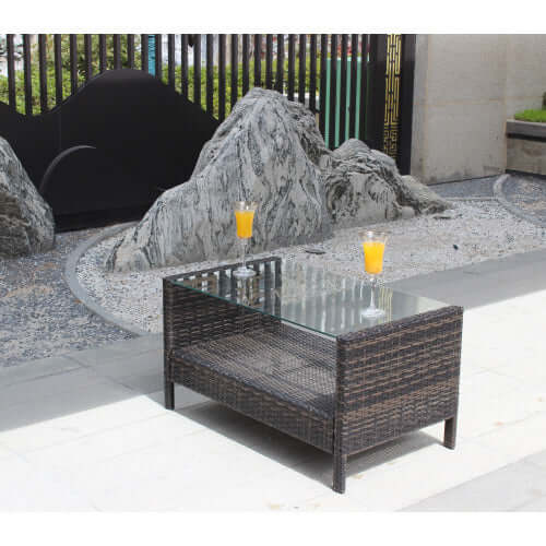 35-inch rectangular coffee table made of weather-resistant brown PE rattan with a tempered glass top in an outdoor setting.