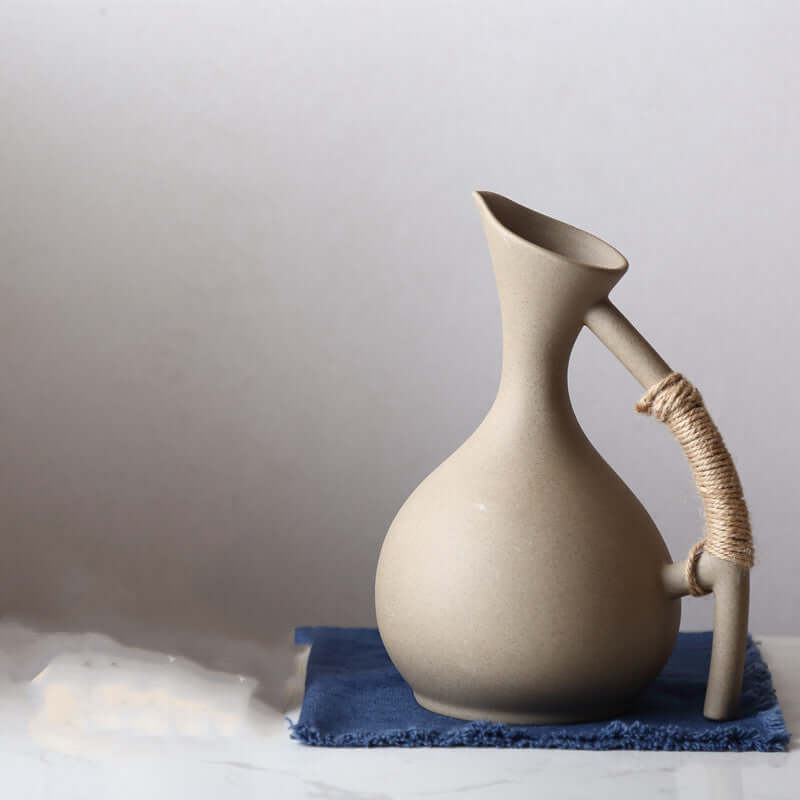 Handcrafted ceramic kettle set on a blue cloth, featuring a minimalist Nordic design for serving cold beverages.