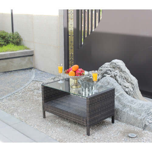 35 inch rectangular coffee table made of weather-resistant brown PE rattan with a tempered glass top in an outdoor setting.