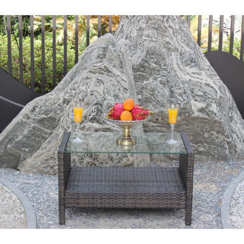 35" rectangular outdoor coffee table with glass top featuring colorful fruits and drinks, surrounded by nature.