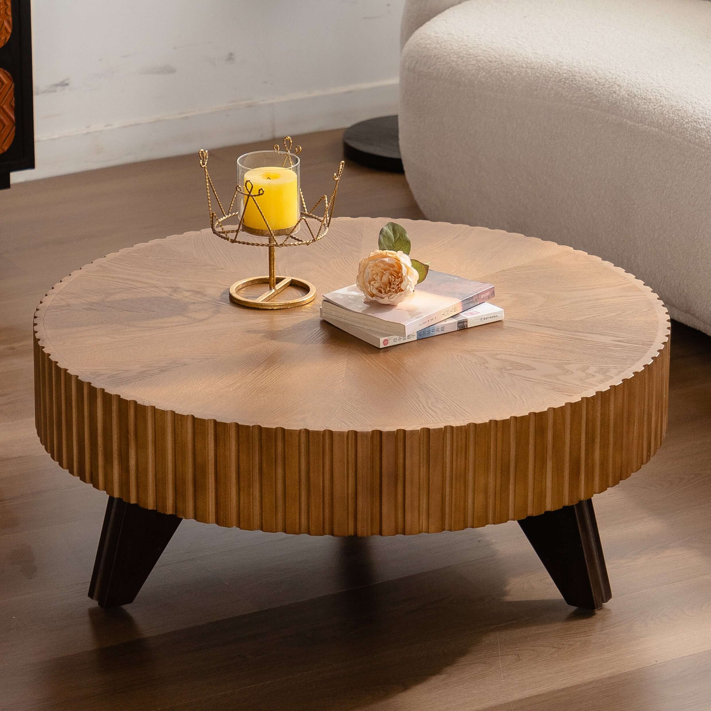 35.4" round retro coffee table with natural oak finish, featuring a stylish design, books, a flower, and a candle on top.