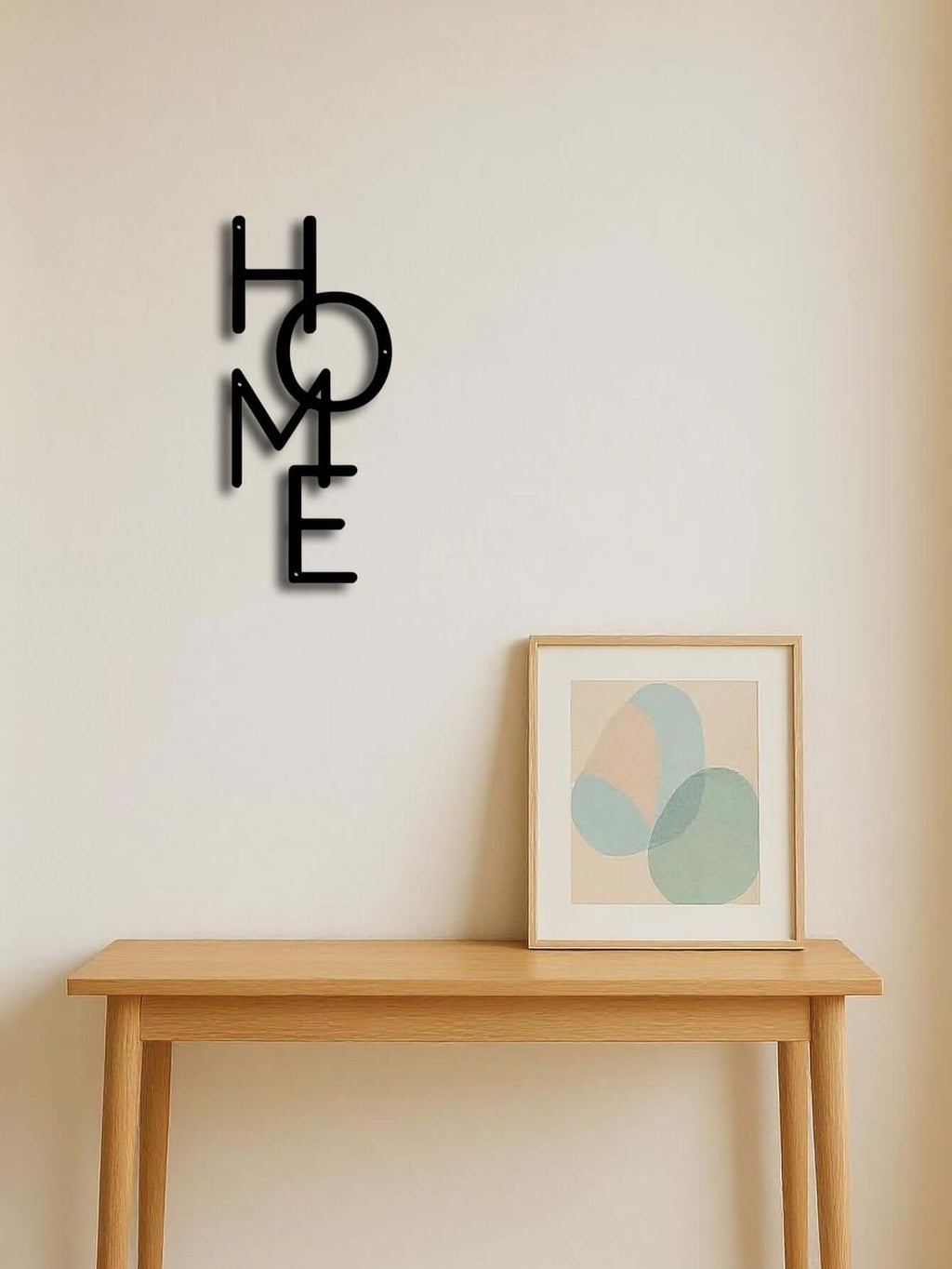 Minimalist metal "HOME" wall art sign displayed above a wooden table with framed art, adding modern decor to a cozy space.
