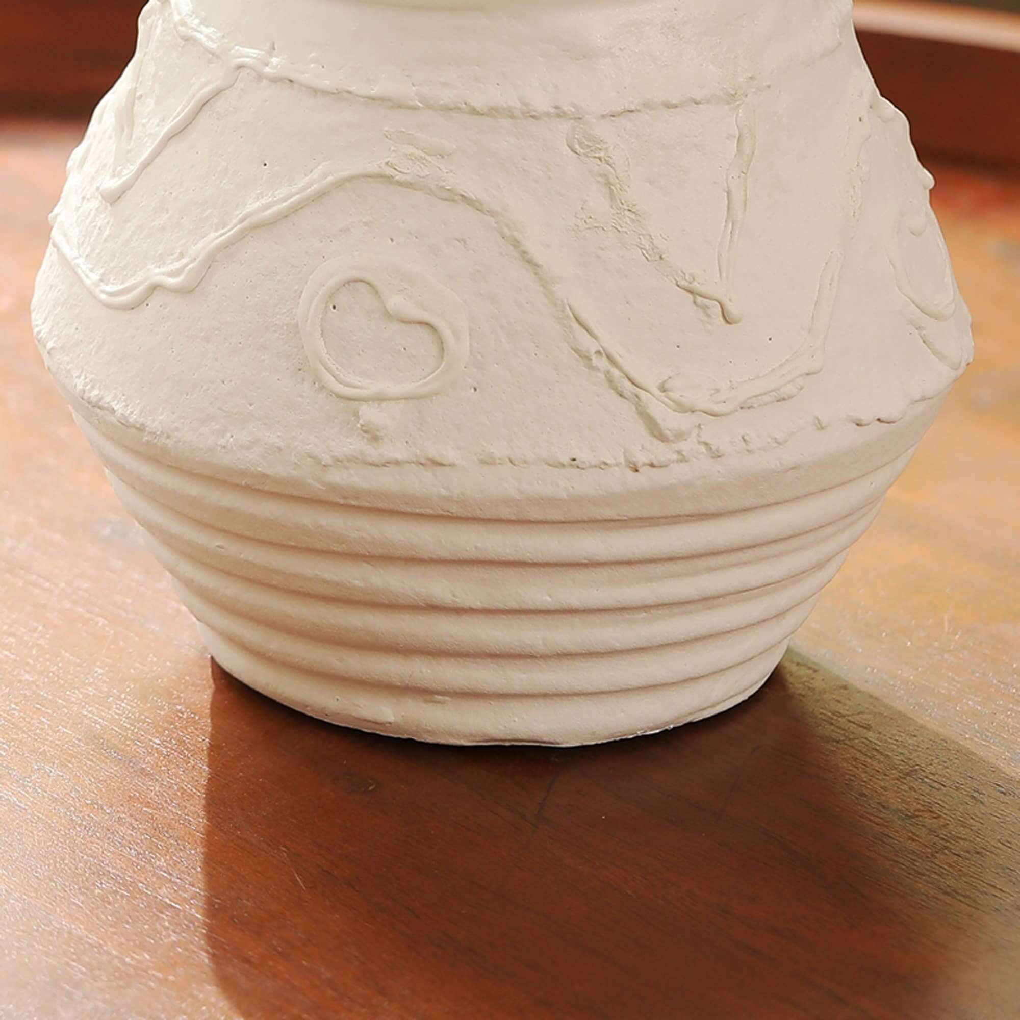 Close-up of a rustic terracotta candle holder with organic patterns, showcasing unique textures and soft white hue.